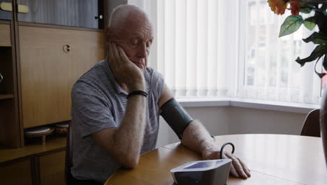 senior man checking blood pressure at home