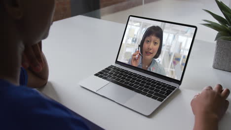 mujer de negocios afroamericana sentada en un escritorio usando una computadora portátil haciendo una videollamada con una colega
