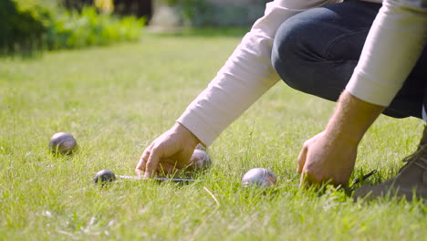 side view of a caucasian young man calculating distance between petanque balls in the park