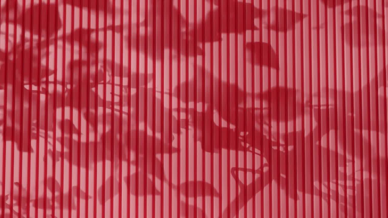 Shadow of tree branches and leaves on vertical red corrugated metal wall. Abstract natural light and linear pattern background. Design for wallpaper, banner, postcard, greeting card, poster, header.