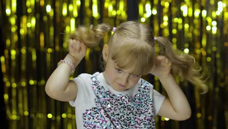 niño bailando, celebrando la victoria, haciendo tonterías. niña posando en el fondo con cortina de aluminio