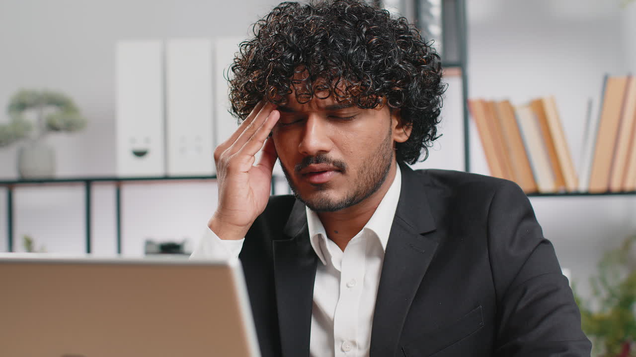 Tired indian business man suffering from headache problem tension migraine stress at home office