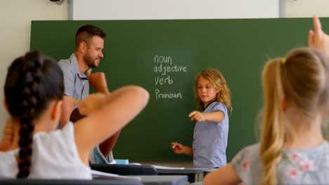 group of students sitting at desk and raising hands in classroom at school 4k