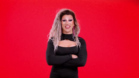 Portrait of a confident drag queen with arms crossed against a red background