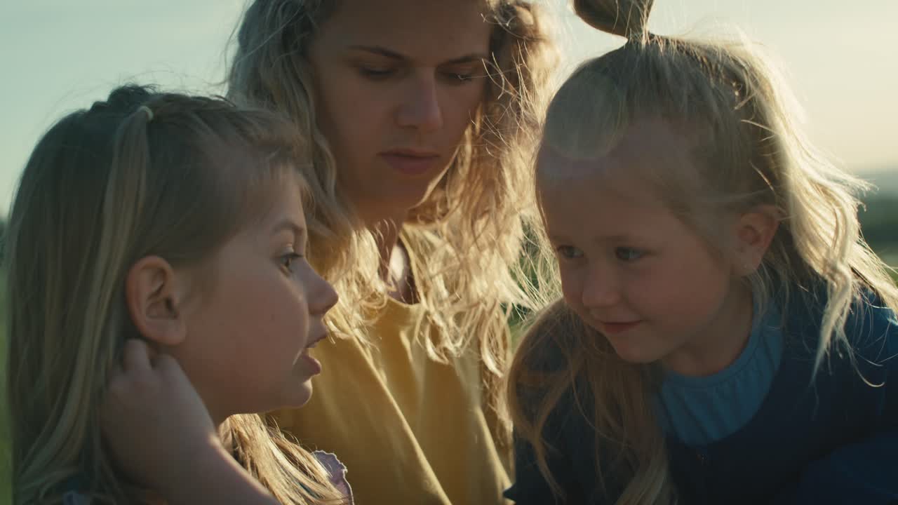 엄마와 두 명의 어린 딸들이  ⁇ 을 맺고 초원에서 함께 시간을 보내고 있습니다.