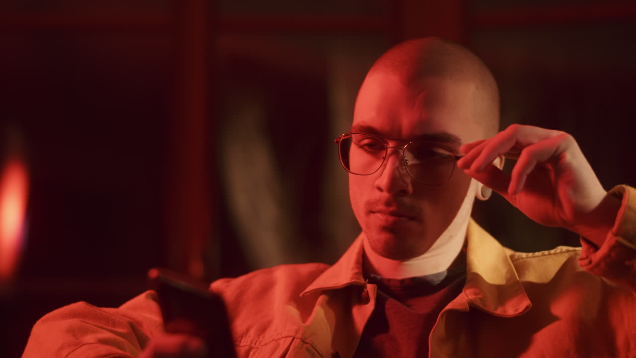 Young Man Looking at Phone in Red Light