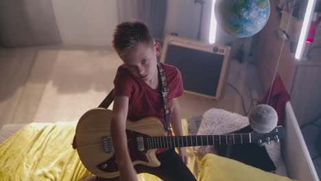 teenager playing electric guitar in bedroom