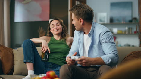 Two-people-competing-arcade-game-living-room.-Proud-woman-winner-sitting-couch