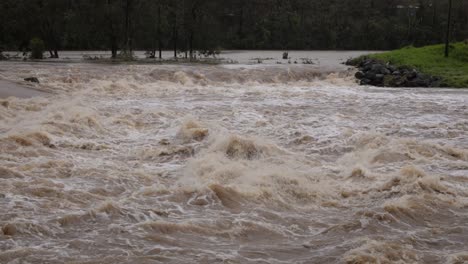 Coomera,-Costa-Dorada,-2-De-Enero-De-2024---Agua-Turbulenta,-Calzada-Del-Río-Coomera-Bajo-Las-Aguas-De-Las-Inundaciones-De-Las-Tormentas-De-2024-En-Enero