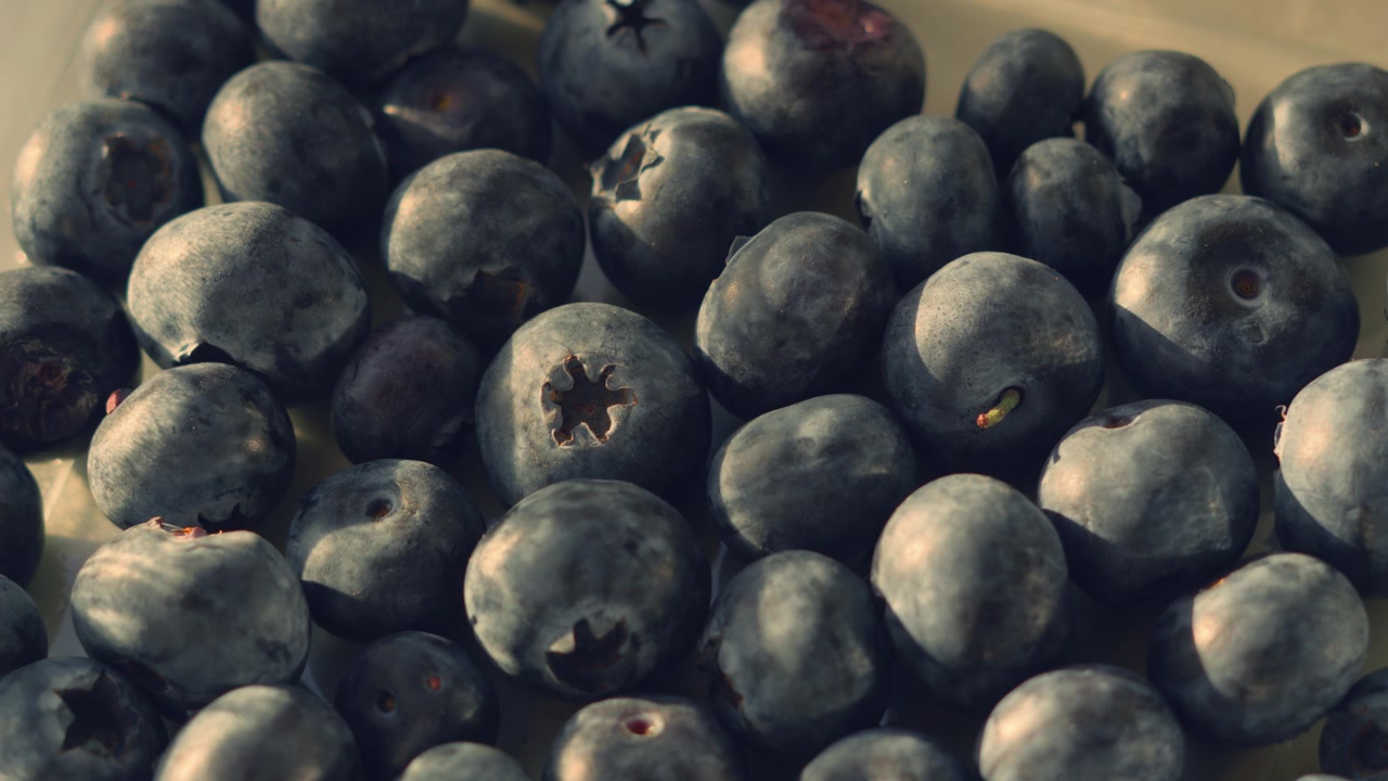 Vista dall'alto di mirtilli freschi e dolci alla luce naturale del sole con rotazione lenta. Perfetto per progetti a tema salute, nutrizione e colazione. 4K