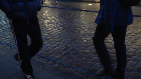 people walking through a street with cobblestones