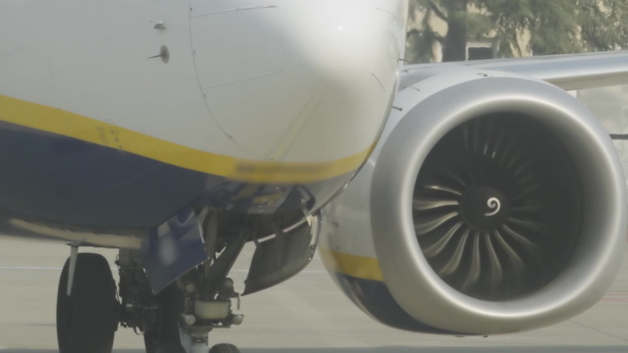 Turbina a rotazione rapida su un grande aereo con ala e ruote del carrello di atterraggio con muso anteriore.