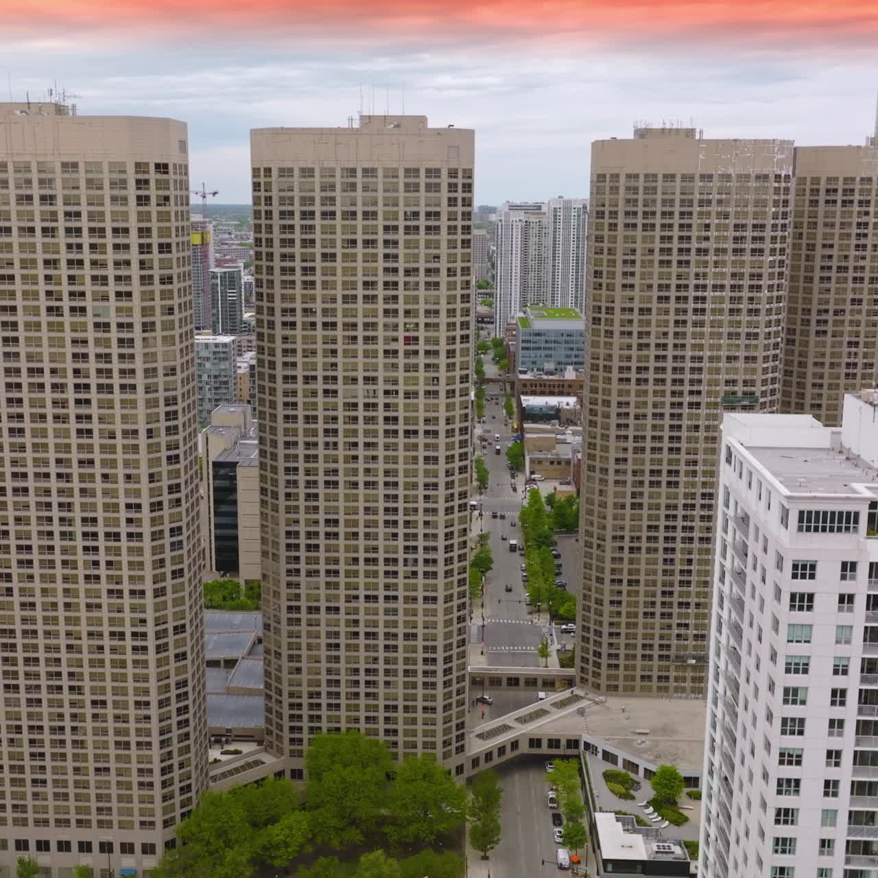 Flight among the buildings of beautiful Chicago. Numerous cars on the roads of city and on the parking lots. Metropolis at sun dusk
