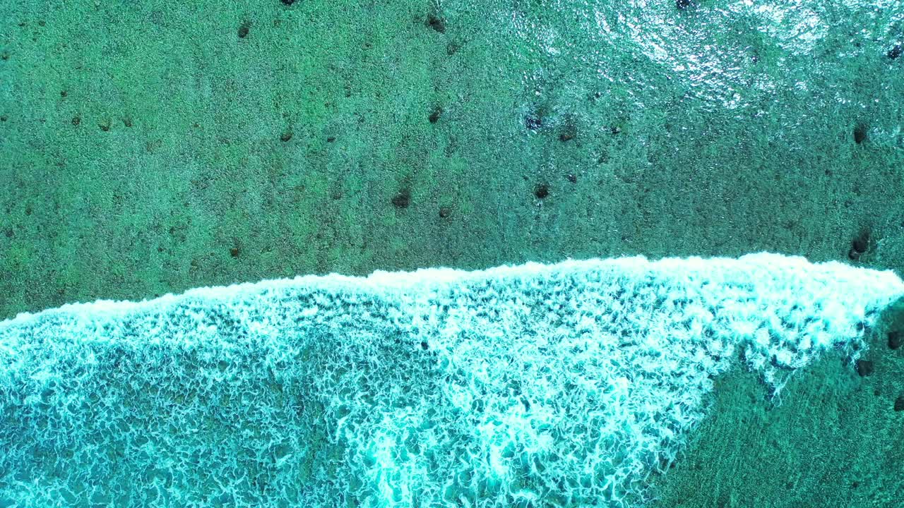 Blue waves crashing into the shore in exotic holiday beach location of Antigua captured from the air