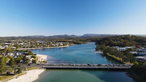 Eine-Belebte-Städtische-Stadtbrücke,-Die-Sich-über-Das-Klare-Wasser-Der-Meeresmündung-Mit-Blick-Auf-Die-Berge-Erstreckt