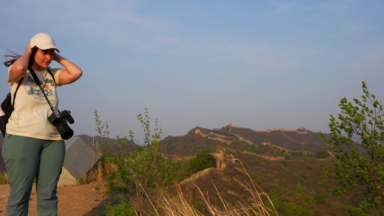 中国の北京のグーベイコウ大壁で日没時に強い風に立ち向かうハイカー写真家