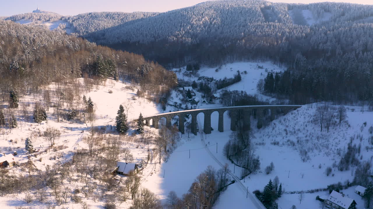 vista aérea de un viaducto de tren de piedra en un valle de montaña de invierno, nieve