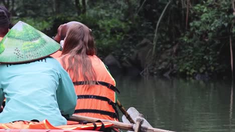two people row gently along a calm river, surrounded by dense vegetation and tranquility.