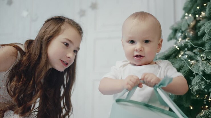 Serious baby boy holding present box in modern apartment