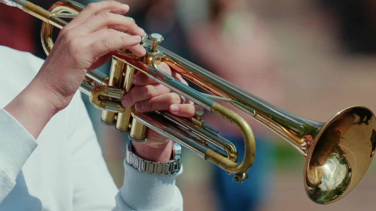 Primo piano di una campana di tromba in ottone che riflette l'ambiente circostante, con una luce naturale soffusa che evidenzia le texture metalliche.