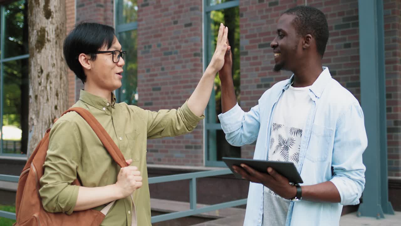 estudiante afroamericano usando tableta en la calle cerca de la universidad