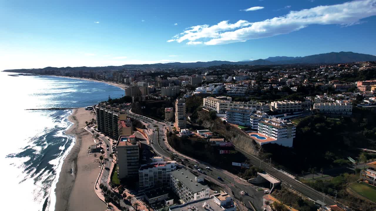 dolly aérea iluminada por el sol de las colinas de fuengirola bulliciosa ciudad costera en españa