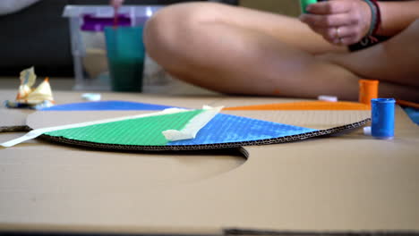 caucasian woman painting a circular cardboard, in order to make a wheel of fortune, low view 4k