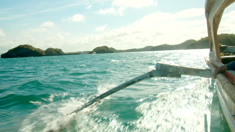 side of philippine bangka boat sailing through tropical blue waters to islands