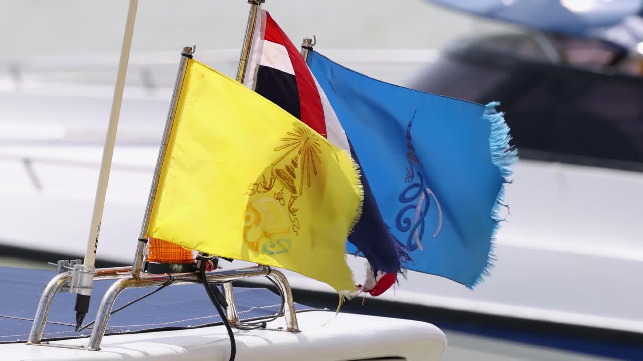 Close-up of colorful flags waving on a boat's rail, showcasing dynamic movement and vibrant colors.