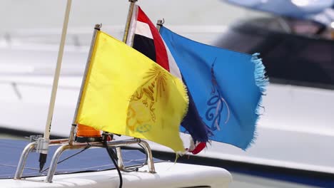 close-up of colorful flags waving on a boat's rail, showcasing dynamic movement and vibrant colors.