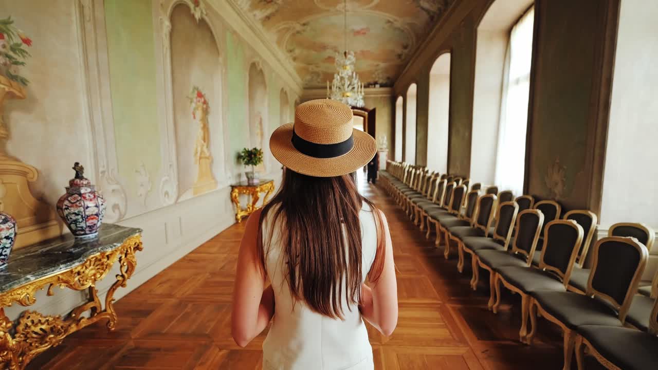 Woman strolls in baroque corridor filled with light, detail, and golden charm