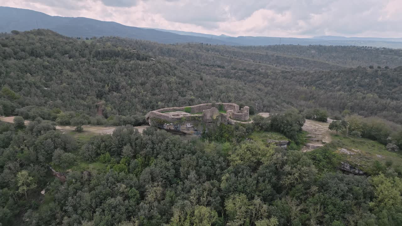 Majestic taradell castle ruins stand atop a rocky outcrop, surrounded by a vast expanse of verdant forest, showcasing a captivating blend of history and nature in the heart of catalonia, spain