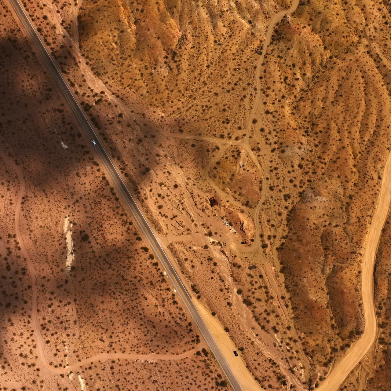 Bird's eye view on the arid desert. Dry landscape with roads and no vegetation. Mojave desert scenery with shadows from clouds