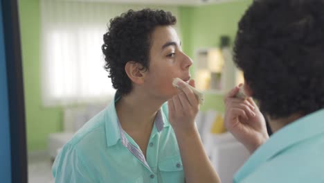 Un-Chico-Gracioso-Y-Lindo-Que-Se-Preocupa-Por-Su-Cuidado-Personal-Se-Está-Aplicando-Crema-En-La-Cara.