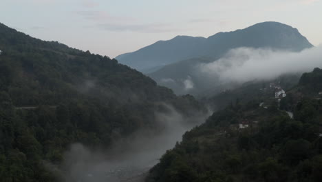 montañas espeluznantes y nubes bajas sobre la corriente del río en los balcanes