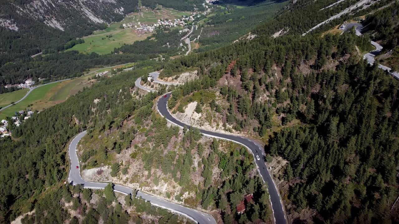 coches circulando por una carretera ventosa en la ladera de una montaña en un valle con excelentes vistas
