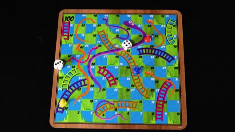 hand moving pieces on snakes and ladders board