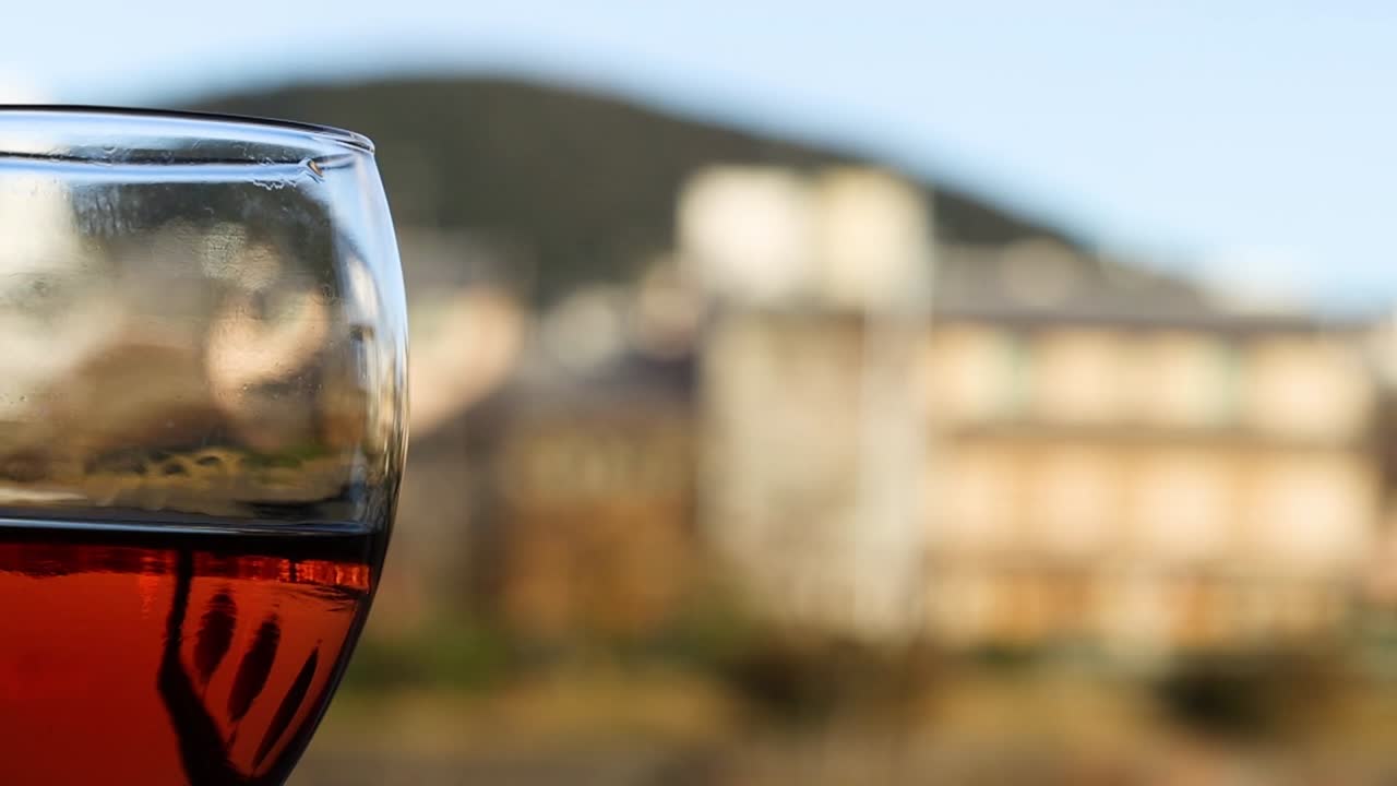 Calice di vino con liquido rosso, paesaggio urbano sullo sfondo
