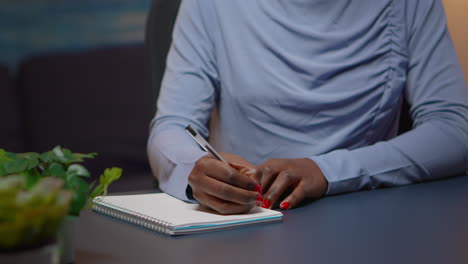 close up of african businesswoman writing list of tasks