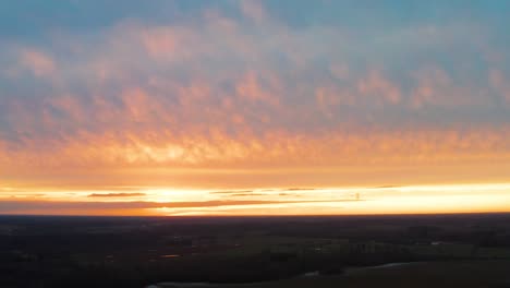 aerial view of dark land during impressive golden hour sunset with clouds