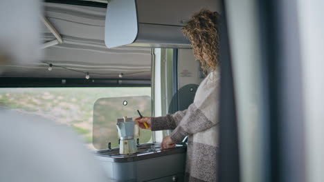 lady putting coffee maker on stove motorhome. woman preparing breakfast in van