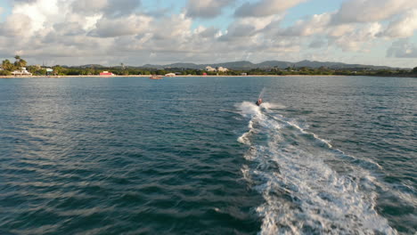 aerial tracking circular view male on jet-ski ride maneuver have fun at full speed with sunset over horizon