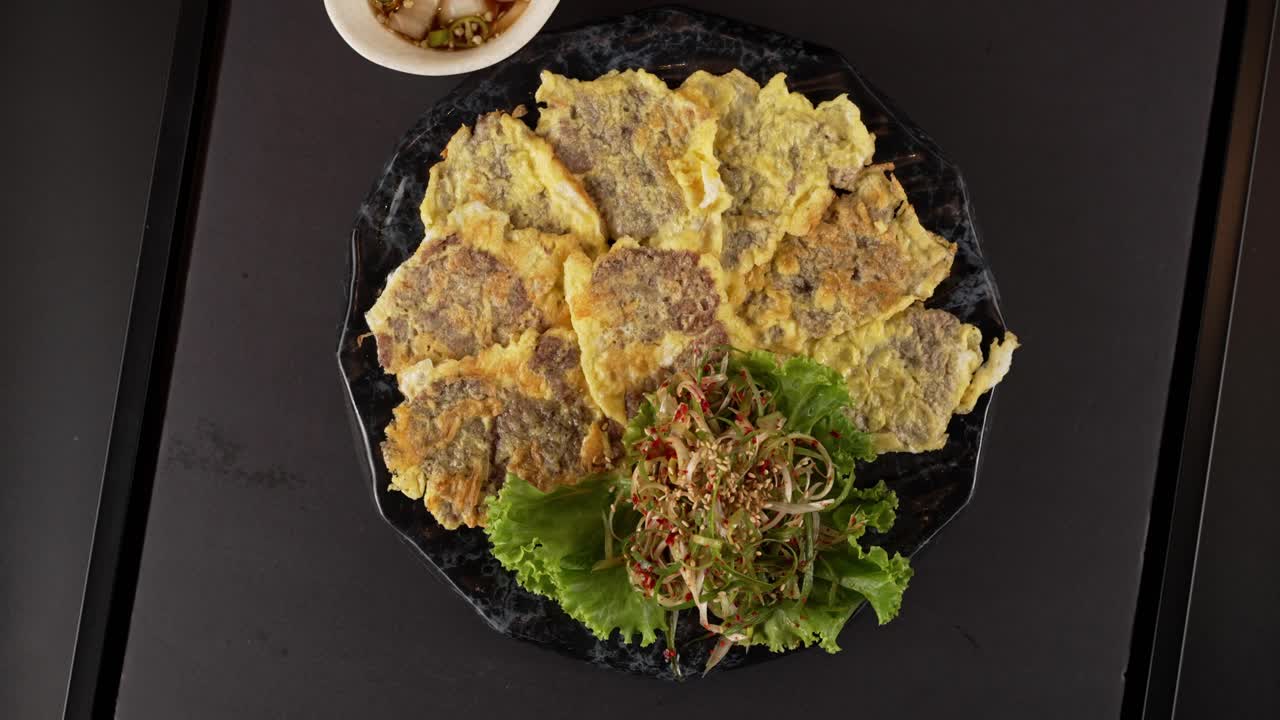 Tender beef coated in egg batter and pan-fried to golden perfection. Best enjoyed with dipping sauce for rich flavor. 부드러운 소고기를 계란 옷을 입혀 노릇하게 부친 전. 양념 간장과 함께 즐기면 더욱 깊은 풍미가 살아납니다.