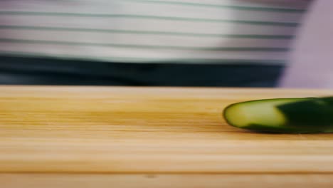 mujer cortando pepino en una tabla de cortar de madera