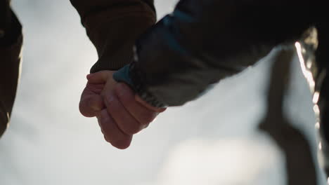 어른과 아이가 손을 잡고 있는 클로즈업, 카메라가 소년을 향해 움직일 때 빛의 부드러운 빛에 부드럽게 조명됩니다.