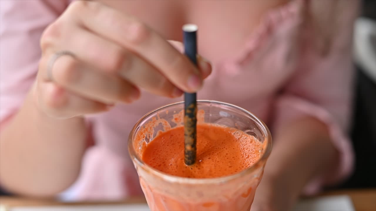 Donna bruna che beve succo di carote e arancia in un ristorante