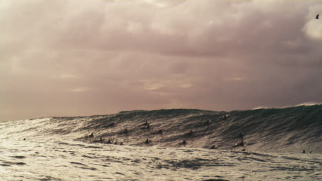 rocky waters grow and churn as crowd of surfers wait to catch a beast