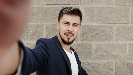 man taking a selfie in front of a brick wall
