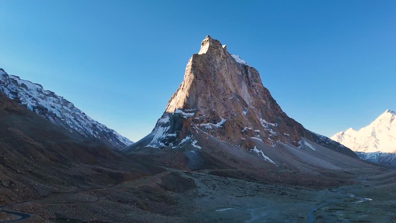 Aerial drone shot showcasing the first light illuminating the peaks of Gumbok Rangan at dawn.