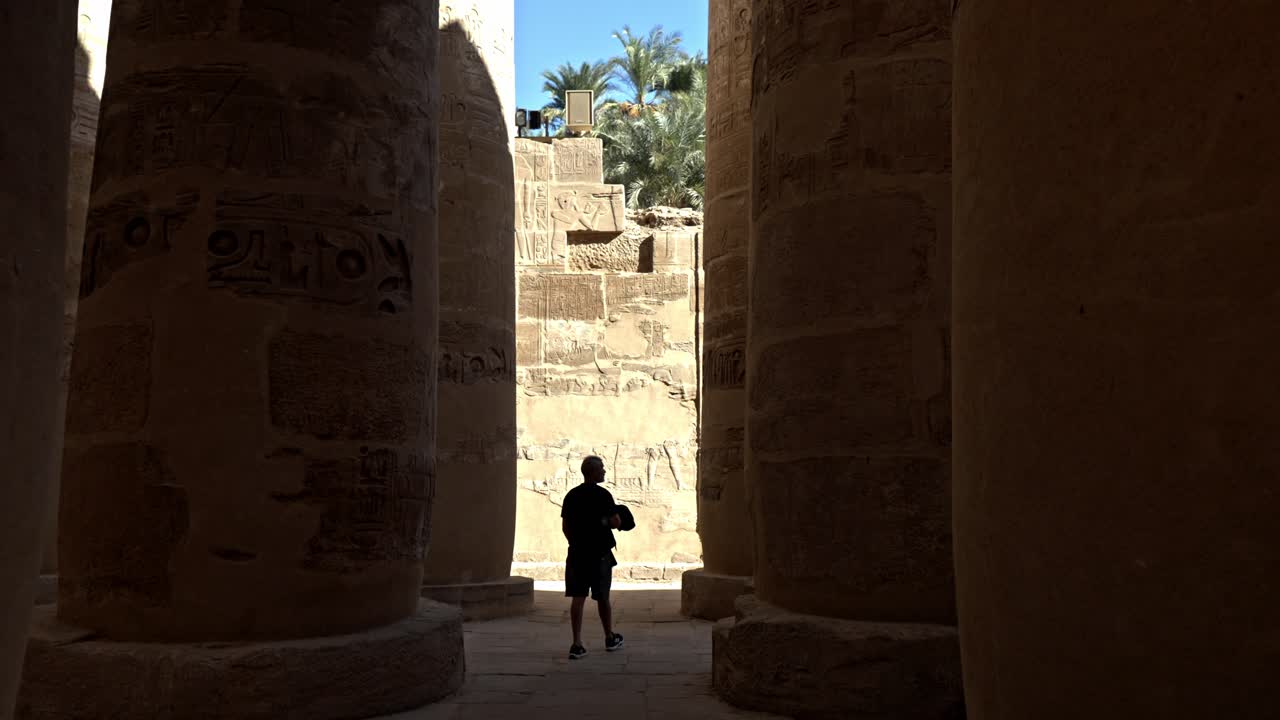 This clip provides a dramatic silhouette of a visitor walking through the Great Hypostyle Hall in the Karnak Temple Complex